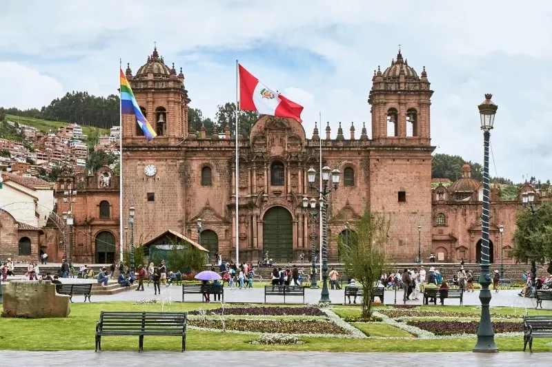 Frontal view of the Cusco Cathedral with the Peruvian and Cusco flags flying in the Plaza de Armas.