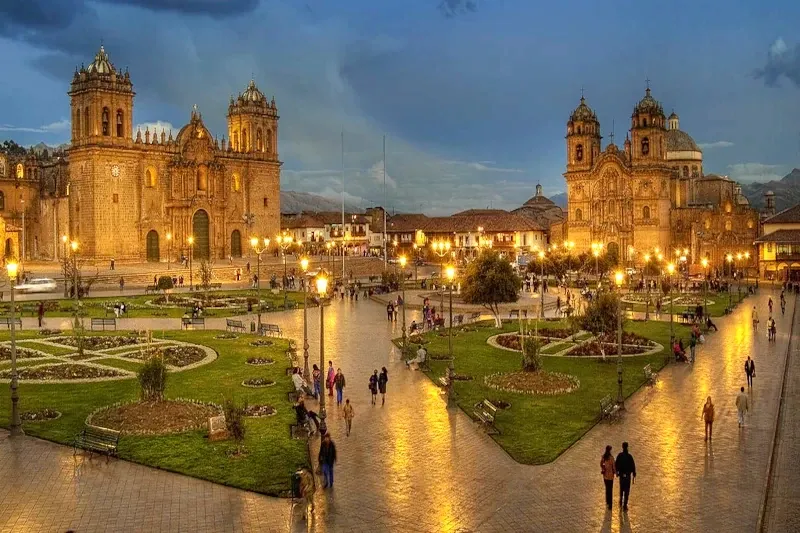 The Plaza de Armas in Cusco at twilight, featuring the illuminated Cathedral and colonial architecture.