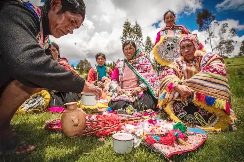 Local Andean women in colorful traditional clothing performing a ceremony or gathering in the highlands of Cusco, Peru.