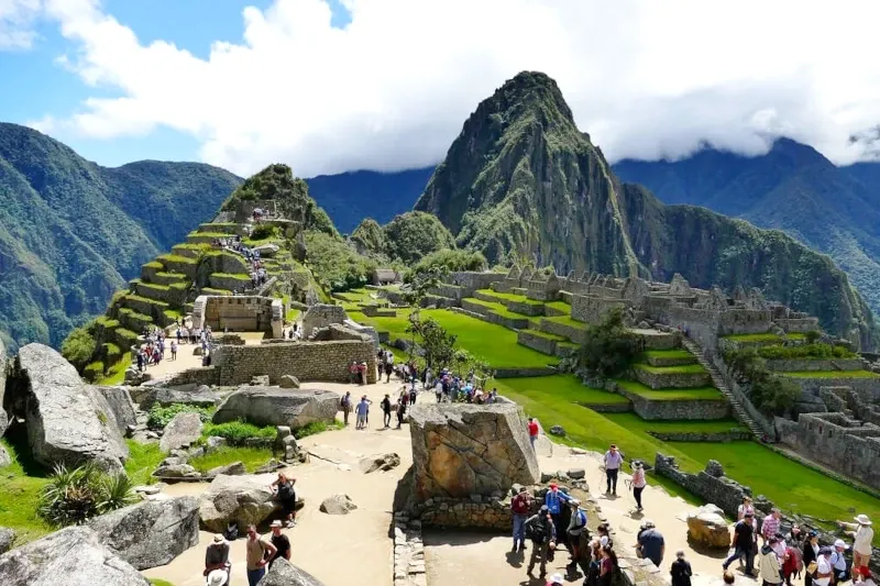 Tourists exploring the main square and stone structures of the Machu Picchu archaeological park.
