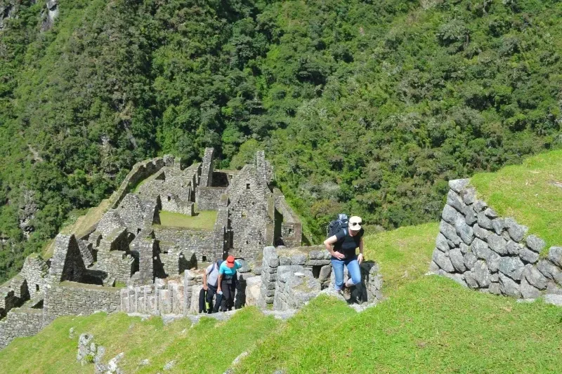 A group of trekkers climbing the stone stairs of the Wiñay Wayna archaeological site on the way to Machu Picchu.
