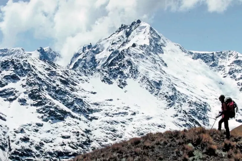 Professional hiker with a backpack trekking through the snowy Salkantay pass during a high-altitude adventure in the Andes.