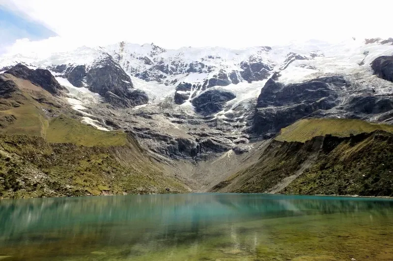 A panoramic view of the turquoise Humantay Lake at the foot of the snow-capped Humantay Mountain in Cusco, Peru.
