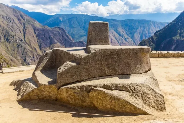 A wide view of the Intihuatana ritual stone at the highest point of the Machu Picchu citadel, showcasing the precision of Inca stonework.