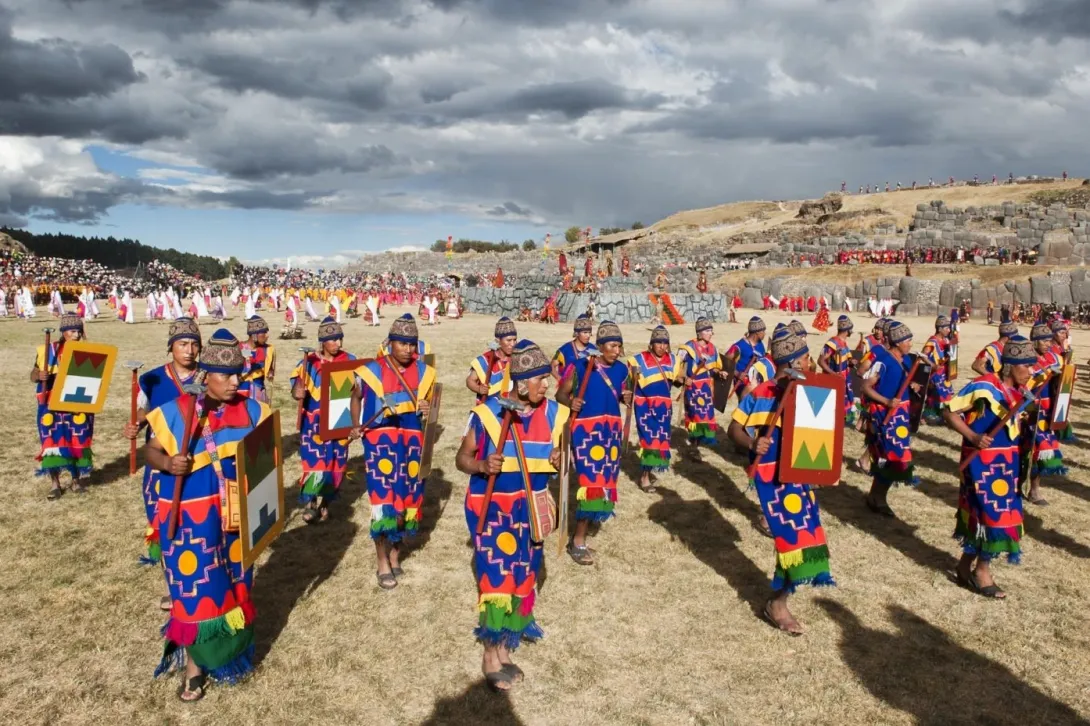 Incan warriors in traditional blue and red tunics carrying shields during the Inti Raymi ceremony at Sacsayhuaman.