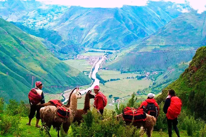Local Andean people with llamas overlooking a fertile valley in Cusco, representing the traditional lifestyle and culture of the Sacred Valley.
