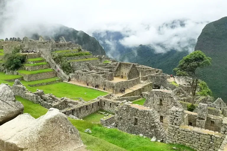 Wide view of the Machu Picchu archaeological site featuring the main urban sector and surrounding mountains in the mist.