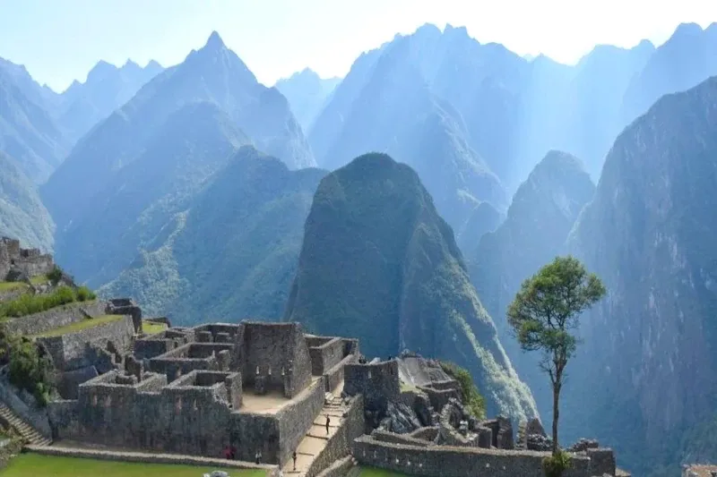 Panoramic view of Machu Picchu ruins with the stunning blue peaks of the Andes Mountains in the background.