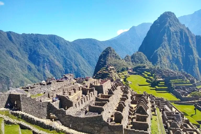 Wide angle view of the Machu Picchu sanctuary in Peru on a bright sunny day showing the main plaza and surrounding mountains.