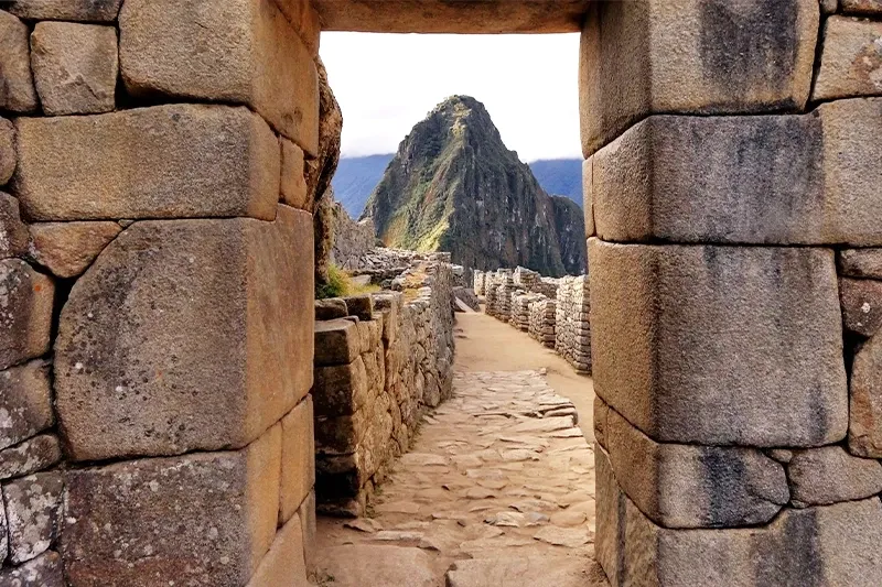 A view through a traditional Inca stone doorway looking towards the Huayna Picchu mountain at the Machu Picchu archaeological site.