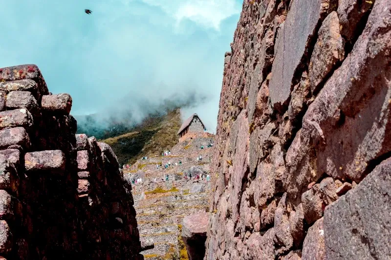 Close-up of ancient Inca stone walls at Machu Picchu with the Guardhouse in the background, illustrating precise architectural alignment with the stars.