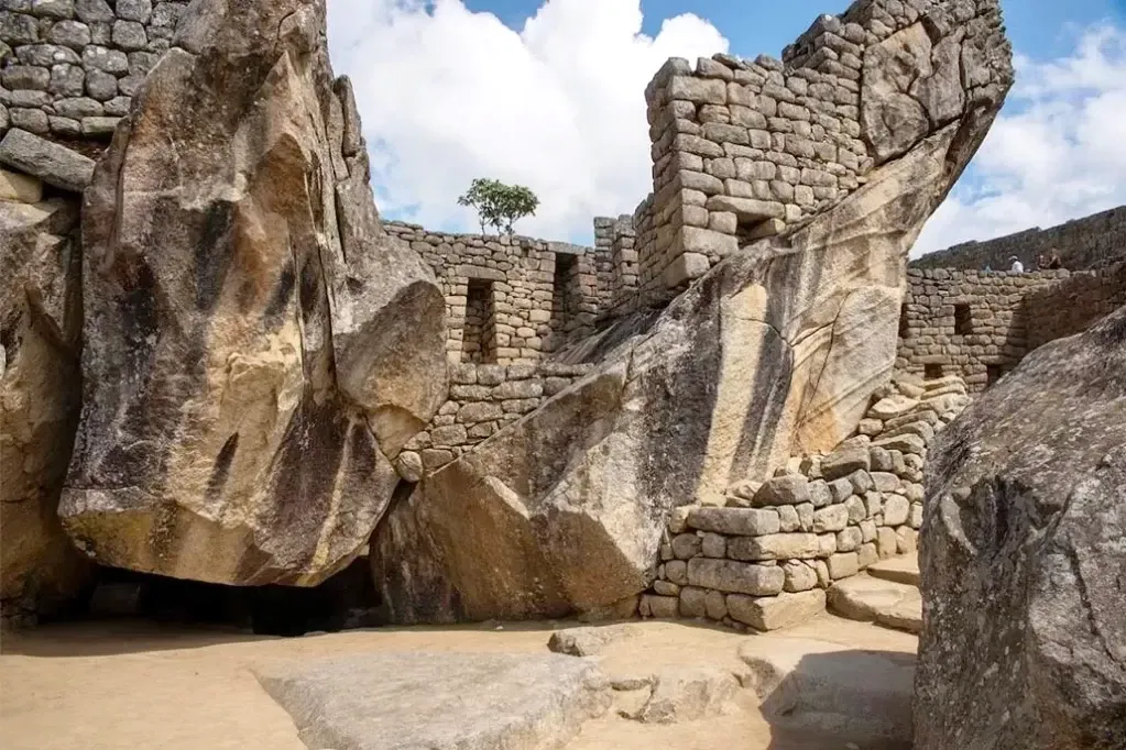 Massive natural rocks and Inca masonry forming the Temple of the Condor under a bright sky.