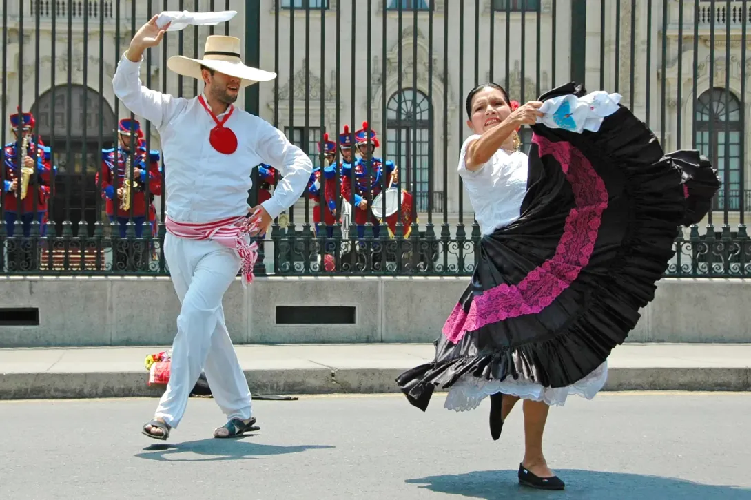 A couple performing the elegant Marinera Norteña, the national dance of Peru, in front of a colonial building.