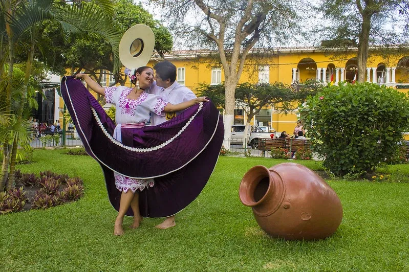 A couple performing the Marinera Norteña, the national dance of Peru, in a traditional courtyard.