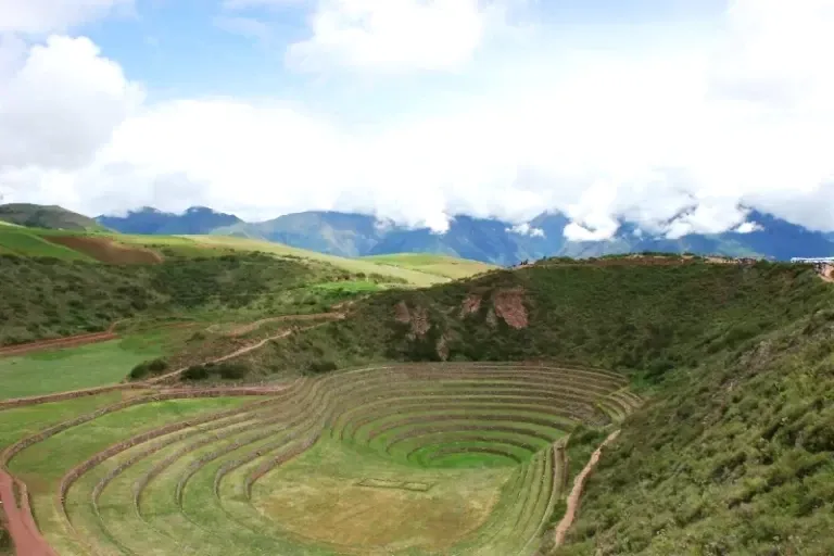 Breath-taking Views of Moray Archaeological Site Wide landscape of Moray terraces with the Andes mountains and white clouds in the background.