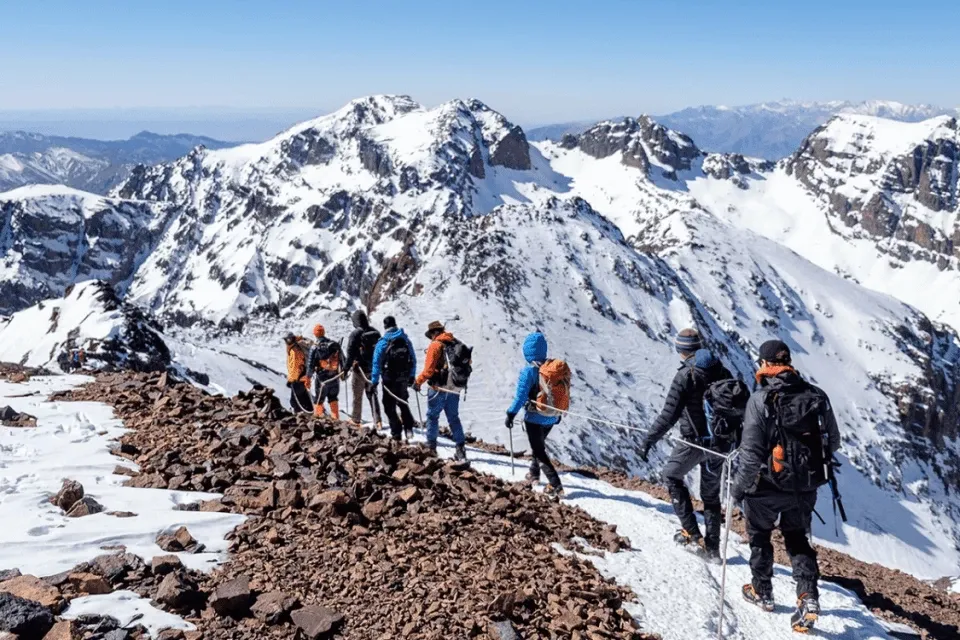 A group of mountain climbers trekking through snow-covered peaks in the Atlas Mountains of Morocco.