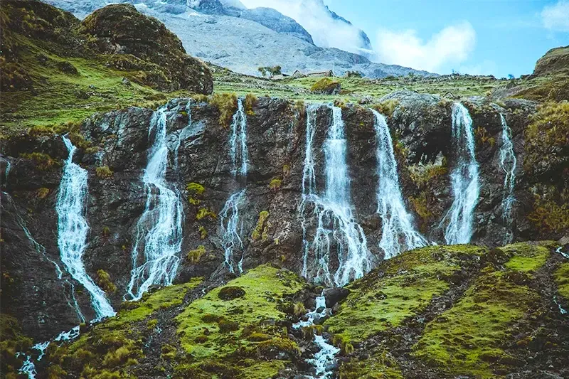 A series of beautiful waterfalls cascading down a rocky mountain face in the Peruvian highlands.