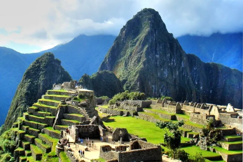 High-angle panoramic view of the Machu Picchu archaeological site with its iconic terraces and Huayna Picchu mountain.