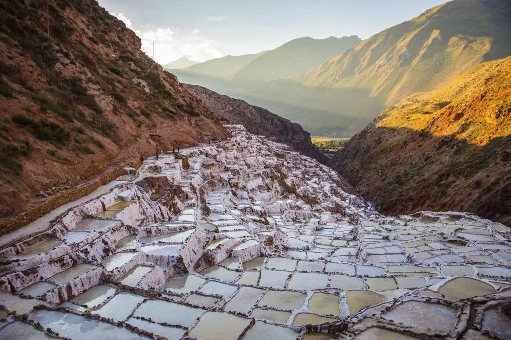 Wide panoramic view of the thousands of salt ponds nestled in a canyon near Cusco during a sunny afternoon.
