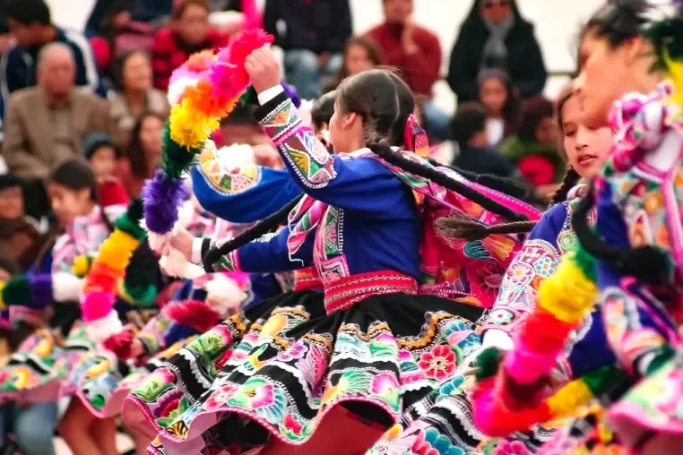 Women in traditional colorful Andean skirts performing a folk dance in Cusco.