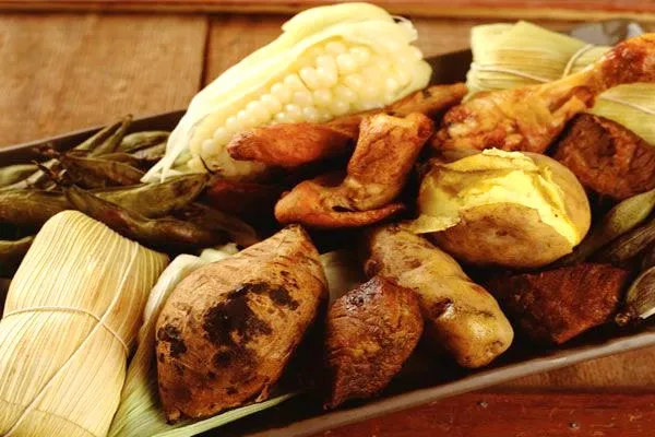 Close-up of a Pachamanca plate with roasted corn, sweet potatoes, and Andean meats, a staple of Cusco's culinary heritage.
