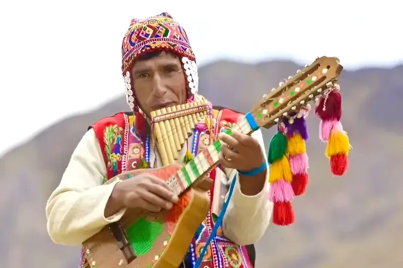 Andean man wearing a colorful chullo playing the pan flute (zampoña) in the Peruvian highlands.