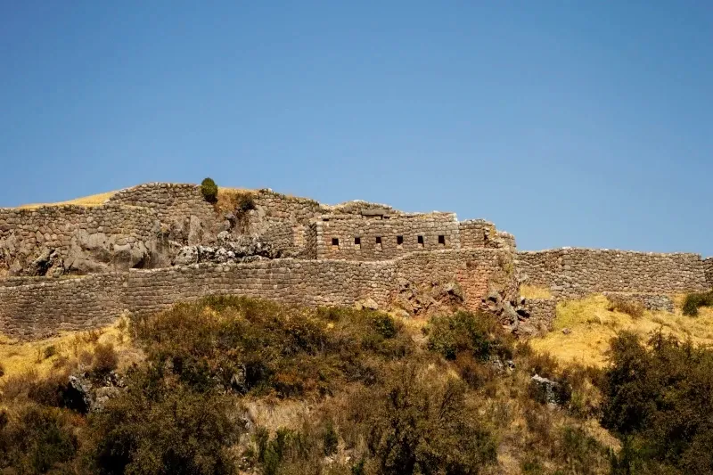Ancient stone ruins of the Puca Pucara fortress on a hill under a clear sky.