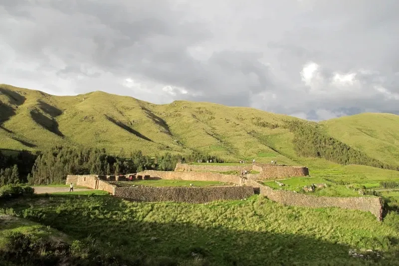 Terraced levels of the Puca Pucara fortress surrounded by green hills.