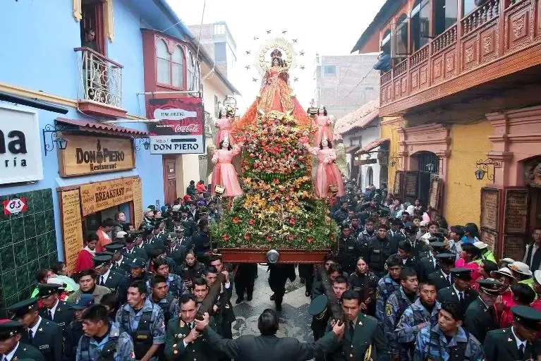 Crowds of people and officers carrying the Virgen de la Candelaria through Puno streets