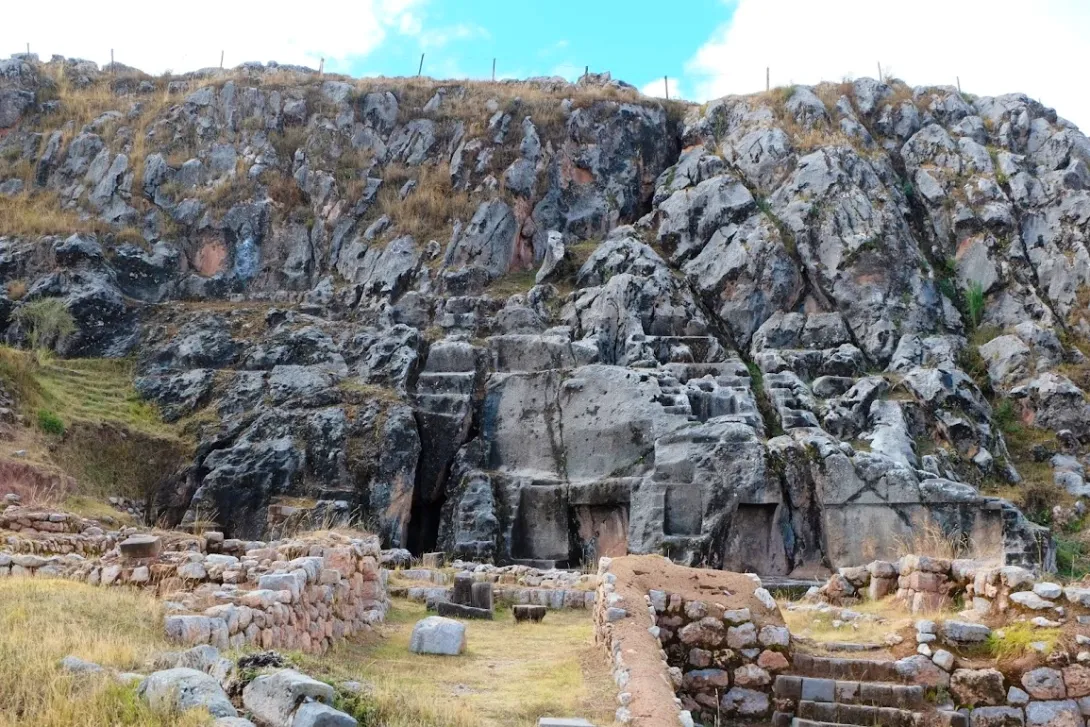 Bright daytime view of the Qenqo ruins showing the terraced stone foundations and the main limestone shrine.