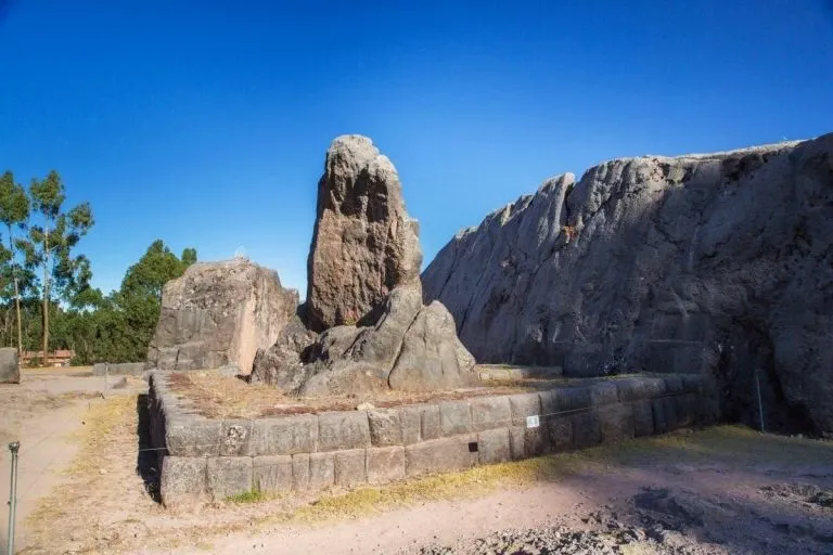 A large stone monolith surrounded by ancient walls at the Qenqo archaeological complex.