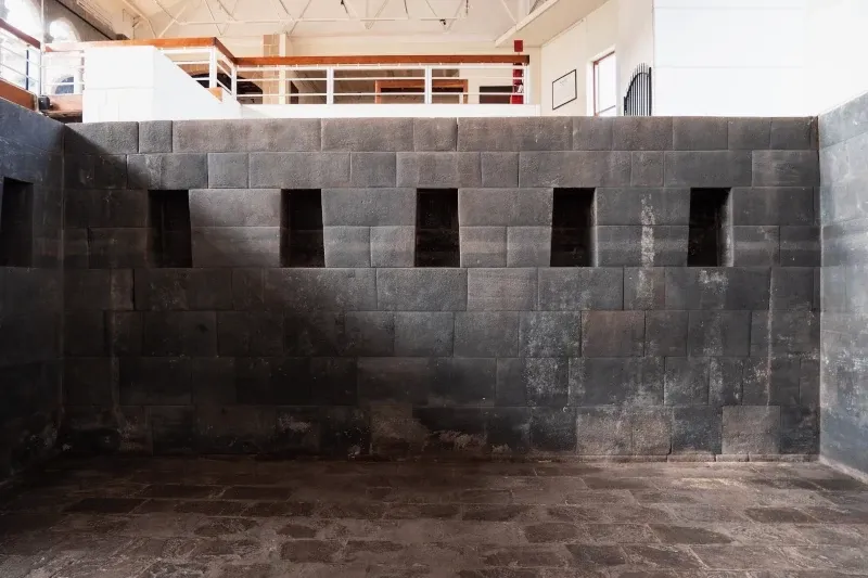 Interior view of the Qorikancha Temple in Cusco showing perfectly carved Inca stone walls and ceremonial niches.