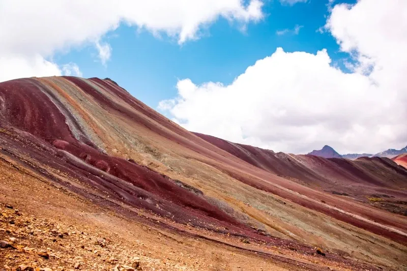 Stunning view of the Rainbow Mountain (Vinicunca) under a blue sky with white clouds.