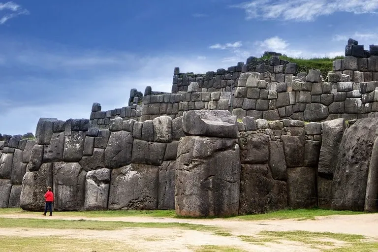 Giant Incan Stones at Sacsayhuaman Large megalithic stone walls of the Sacsayhuaman fortress in Cusco with a person providing scale.
