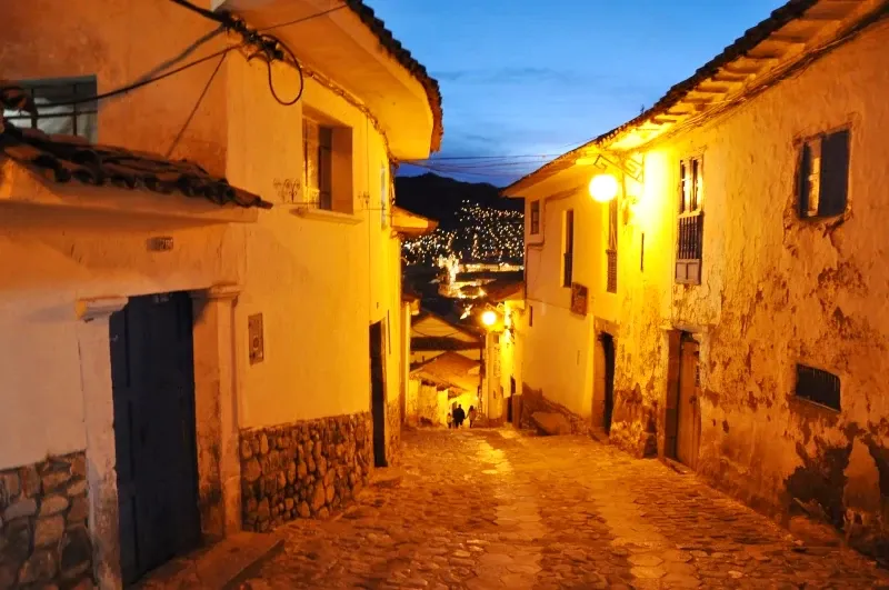 Narrow cobblestone street in San Blas at night with traditional white walls and warm street lights.