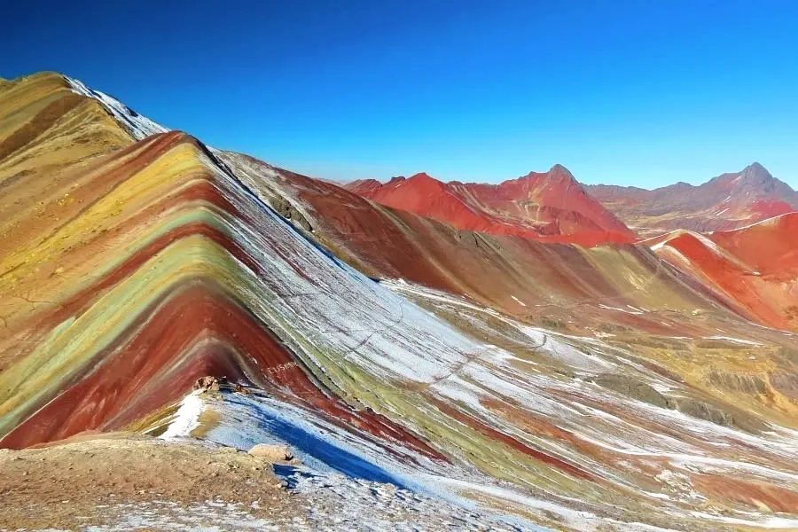 A sharp peak of the Seven Colors Mountain against a clear blue sky in the Peruvian Andes.