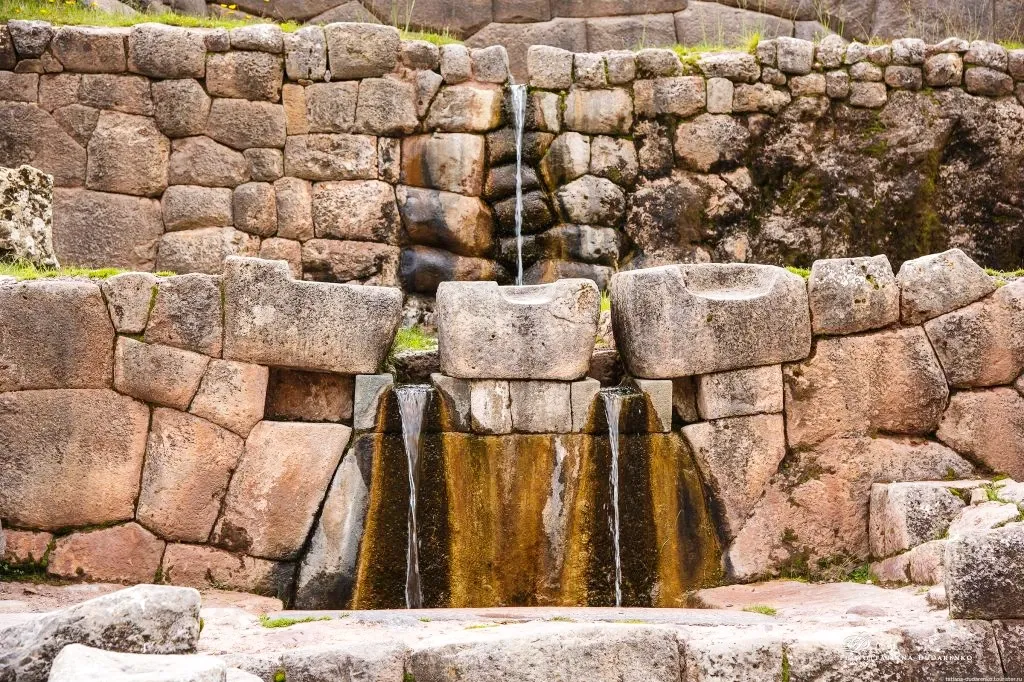 Two symmetrical water streams flowing from the stone walls at the ancient Inca bath of Tambomachay.