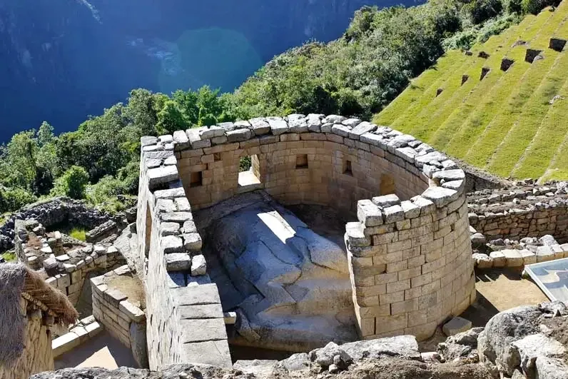 Circular stone wall of the Temple of the Sun in Machu Picchu with sacred rock inside.