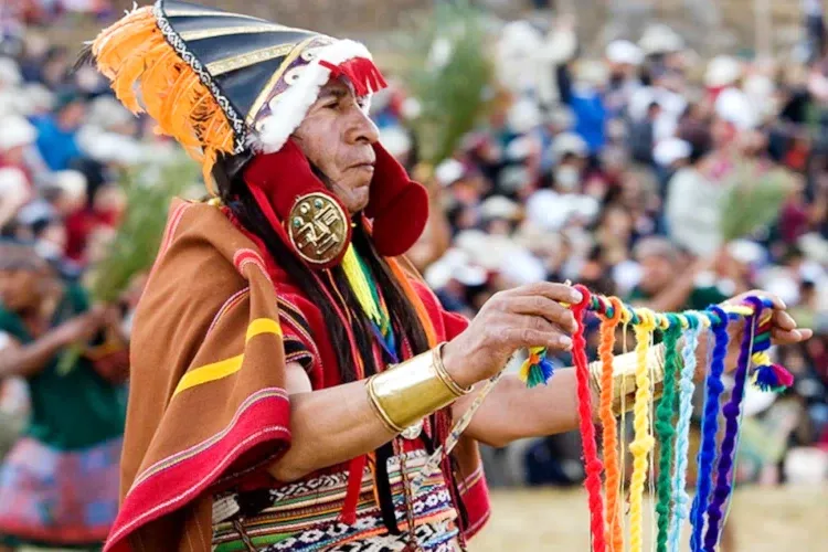 Traditional Inca Quipu An Andean man in ceremonial Inca attire holding a multi-colored Quipu during a cultural reenactment.