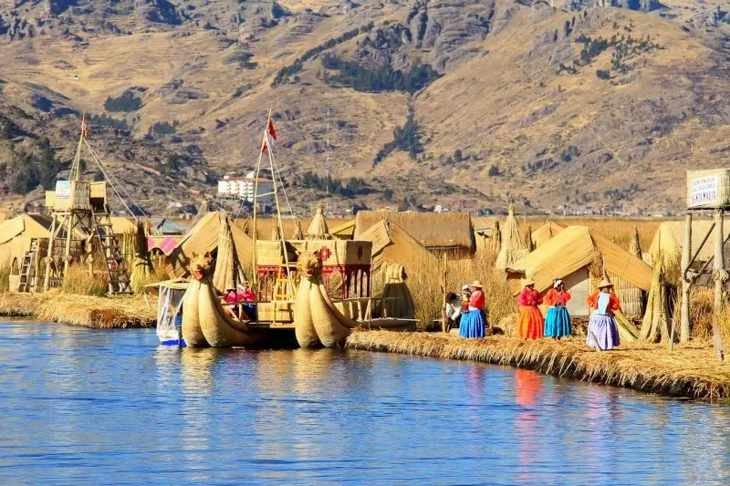 Traditional reed boats and colorful local houses on the Uros floating islands at Lake Titicaca.