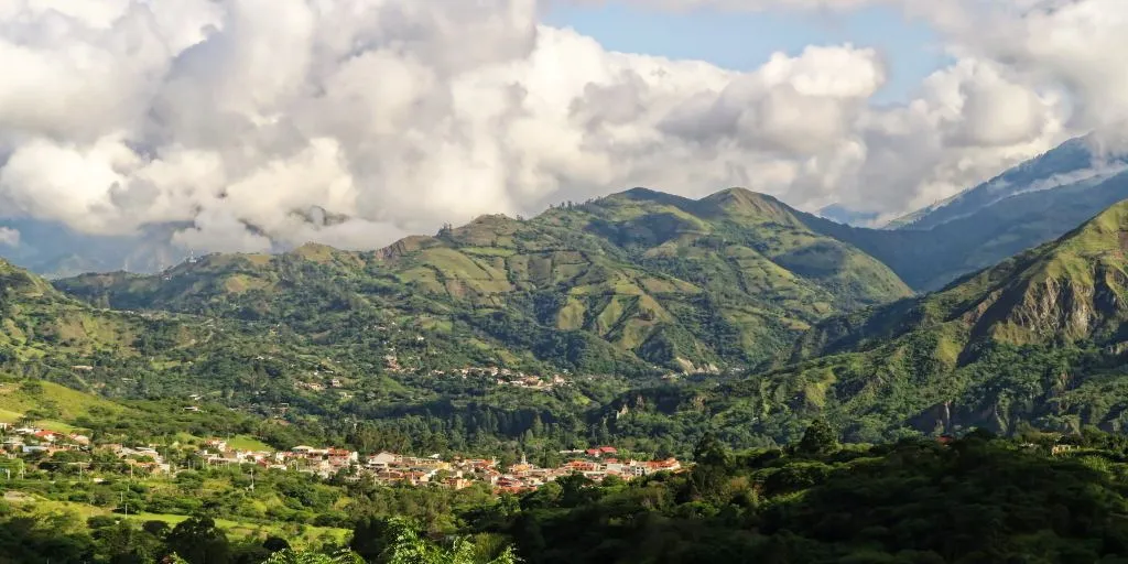 Inca stone walls at the Vilcabamba ruins with clouds descending over the lush cloud forest mountains in Cusco.