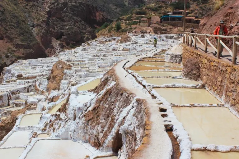 Tourists walking along the stone path next to the ancient salt pans of Maras in the Cusco region.