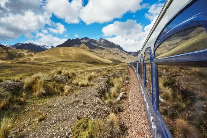 Perspective view from inside a Vistadome train showing the panoramic glass windows and the snowy peaks of the Andes.