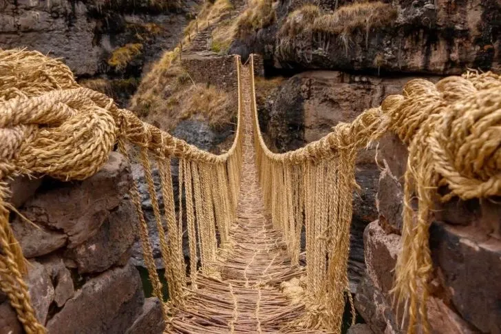 First-person perspective of the handmade grass floor and handrails of Qeswachaka bridge